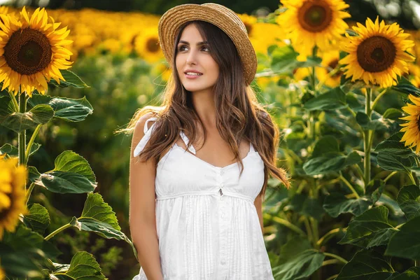 Jovem mulher de vestido branco e chapéu de palha no campo em um dia ensolarado . — Fotografia de Stock