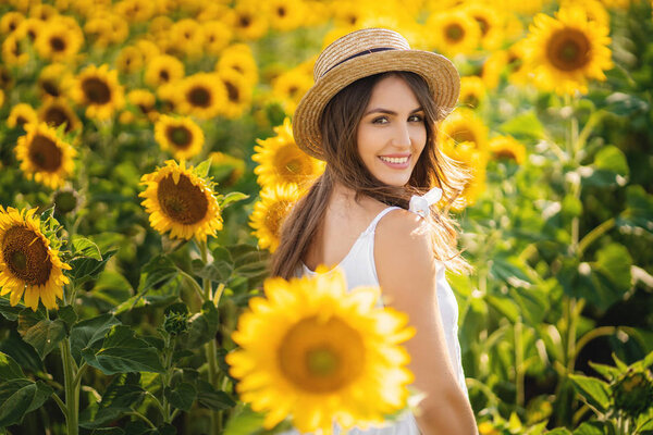 Beautiful young woman in a field of sunflowers in a white dress