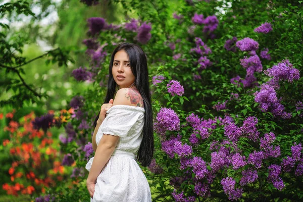Młoda kobieta z tatuażem stwarzające w kwitnącym ogrodzie — Zdjęcie stockowe