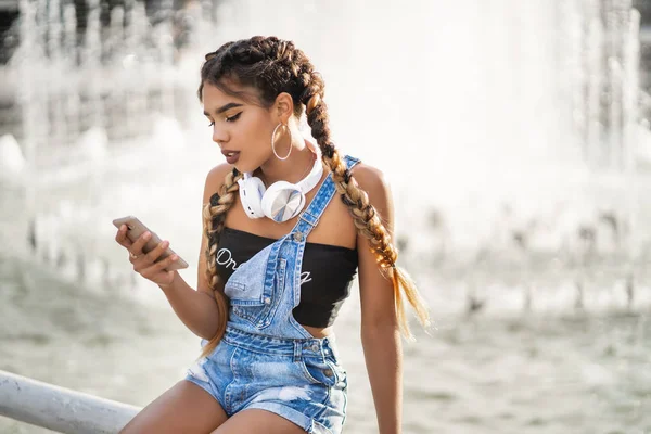 an attractive black young woman adds a new track to her playlist using a mobile app