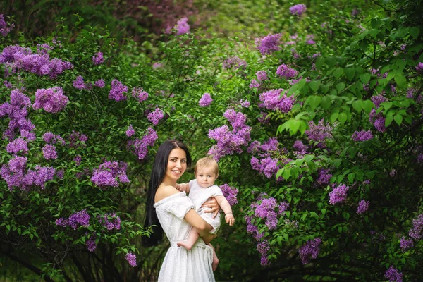 Amante mãe e bebê menina no fundo florescendo flores na primavera . — Fotografia de Stock