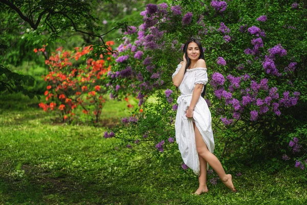 Retrato de niña en vestido blanco delante de las flores púrpuras — Foto de Stock