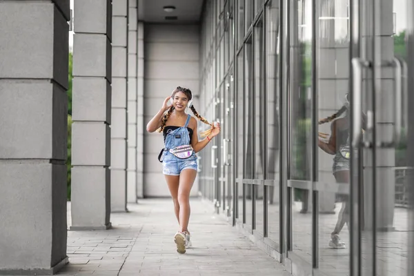 Sonriente jovencita divirtiéndose escuchando música en la ciudad — Foto de Stock