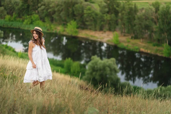 Authentic woman in a straw hat and a white dress on a walk near