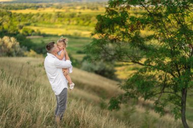 Küçük kız kucaklar ve yavaşça babası öper. Natu üzerinde yürüyün