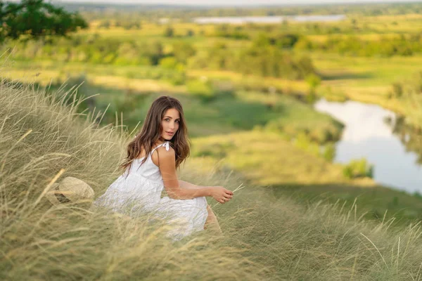 Jolie femme en robe blanche assise sur l'herbe. Nature estivale . — Photo