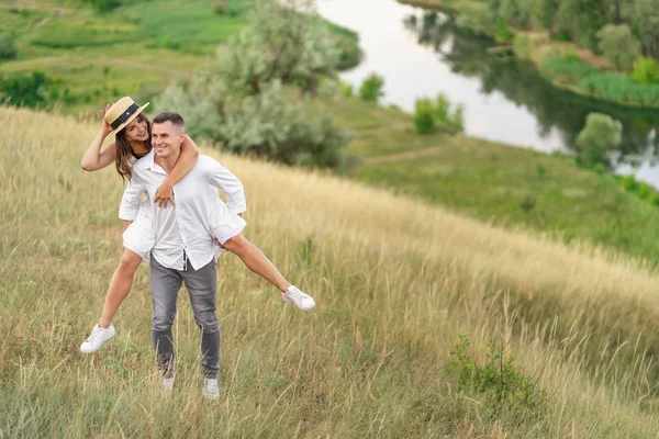 Young guy piggybacking cheerful girlfriend like airplane on the — Stock Photo, Image