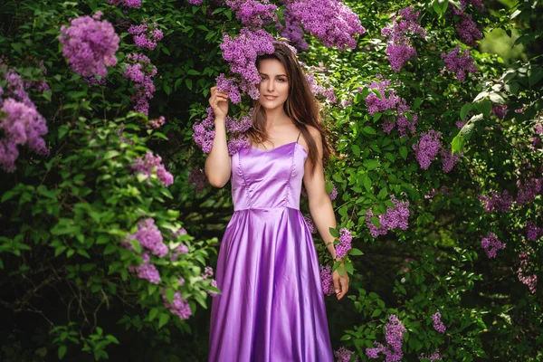 Mulher bonita em vestido roxo posando perto das árvores lilás — Fotografia de Stock