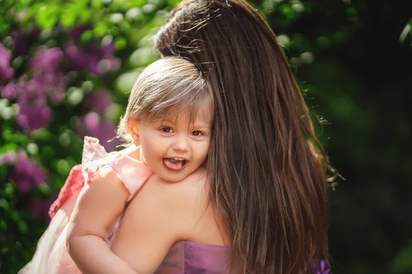 Menina descansando no ombro da mãe. Jardim de primavera no backg — Fotografia de Stock