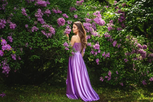 Mujer auténtica en vestido largo cerca de árboles florecientes en gard primavera —  Fotos de Stock