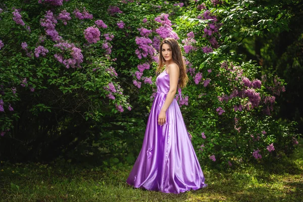 Hermosa mujer joven en vestido largo cerca de los árboles de flores en primavera —  Fotos de Stock