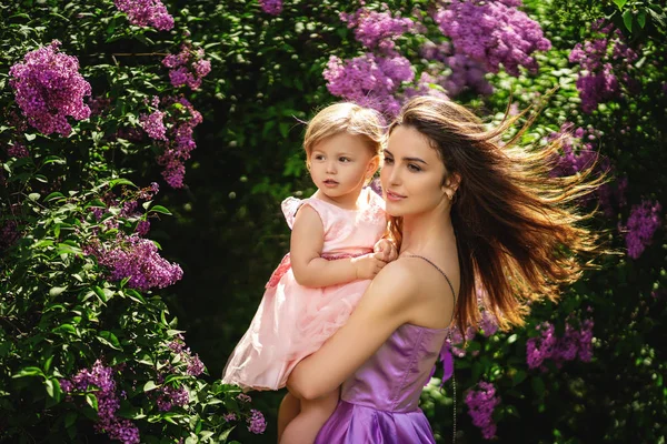 Una giovane madre con un bel sorriso tiene la sua piccola figlia — Foto Stock