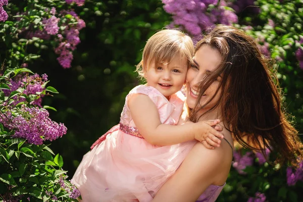 Mulher feliz com criança ao ar livre no jardim da primavera. Eles sorriem e — Fotografia de Stock