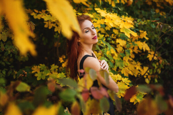 Pretty woman standing among autumn leaves in nature.