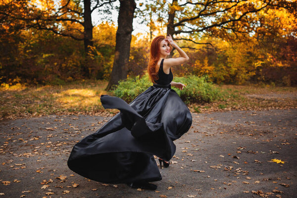 A redhead girl runs in autumn park. She looked back.