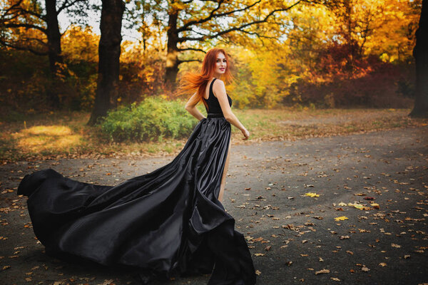 Woman in long dress runs through a forest