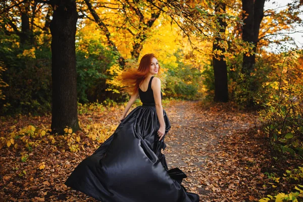 Authentiek meisje op een wandeling in het herfstpark. Lang rood haar ontwikkelt zich Rechtenvrije Stockfoto's