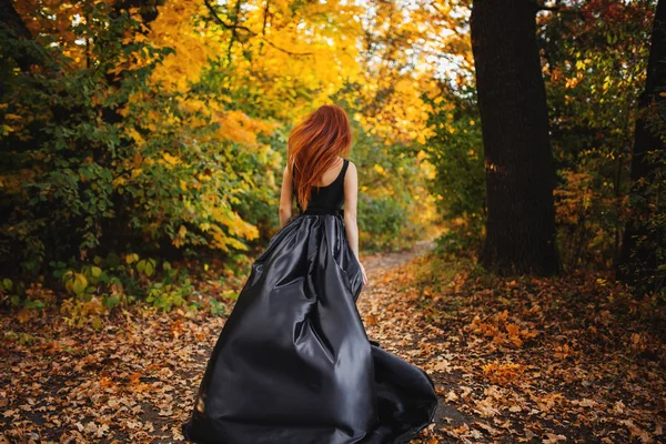 Девушка бежит в осеннем оранжевом лесу. Длинные рыжие волосы развивается в Стоковое Изображение
