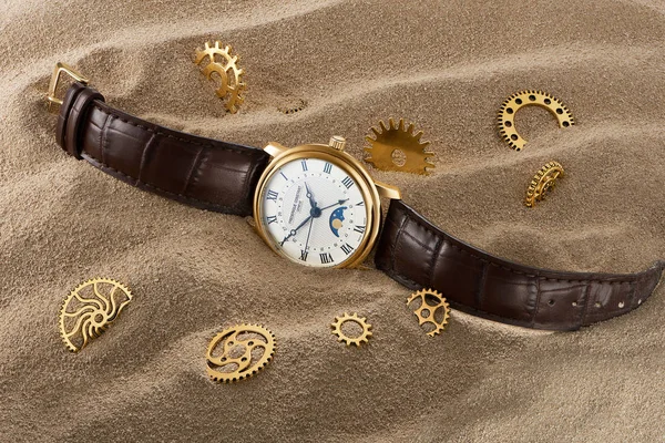 Frederique constant watch on sand with gears Royalty Free Stock Images