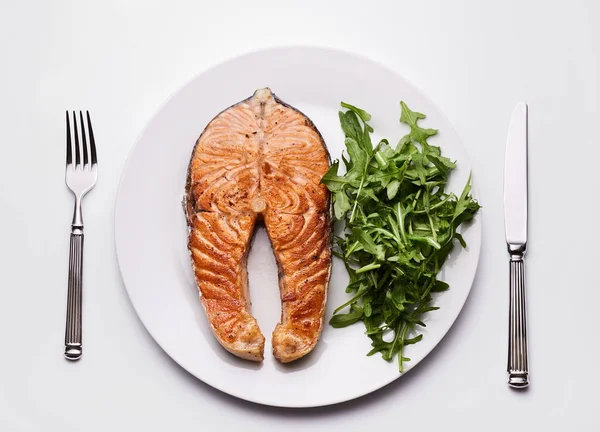 Salmon steak with arugula on plate Royalty Free Stock Images