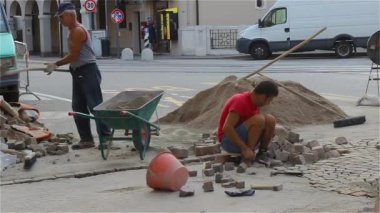 İnşaatçılar Masonlar yolun onarılıyor. Builder kaldırım taşı koyar