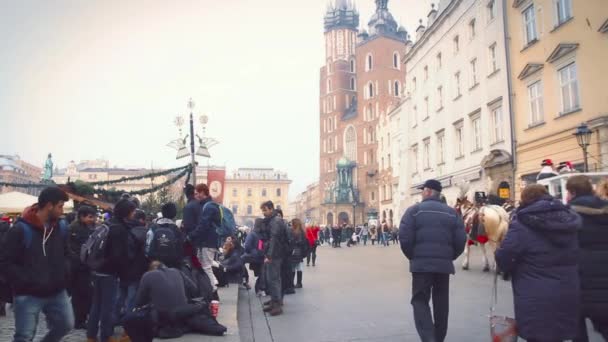 Cracovia, Polonia - 18 de enero: Los turistas pasean por la hermosa calle del casco antiguo. Un grupo de jóvenes se comunica en los terrenos cercanos a la Iglesia de Santa María . — Vídeos de Stock