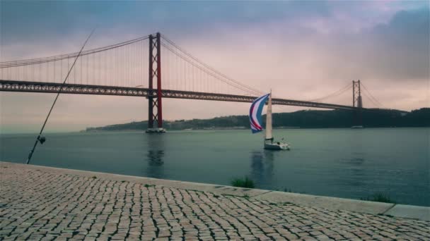 Eine schöne jacht segelt auf dem fluss tagus in der nähe der brücke am 25. april in lisbon — Stockvideo