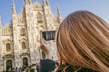 Sarı saçlı bir kızla Milano Duomo bir cep telefonu ile çekiyor.