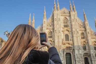 Sarı saçlı bir kızla Milano Duomo bir cep telefonu ile çekiyor.