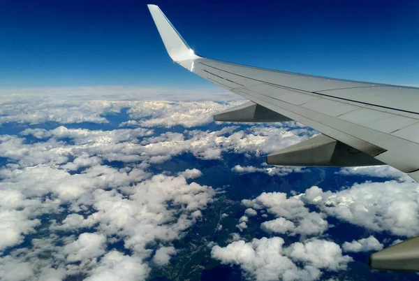 Bergen en witte sneeuw op de toppen onder de vleugel van het vliegtuig tijdens de vlucht — Stockfoto