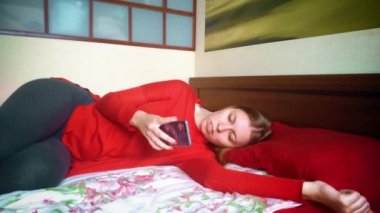 kız telefon tarayıcısında sayfaları çevirir. yatakta dinlenen kız