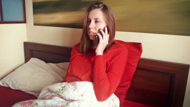一个年轻女子正在用手机说话。在床上的女孩. — 图库视频影像