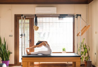 Genç kadın Pilates eğitmeni Pilates Reformer üzerinde egzersiz