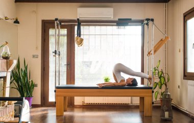 Genç kadın Pilates eğitmeni Pilates Reformer üzerinde egzersiz