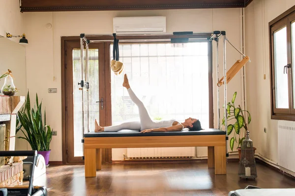 Genç kadın Pilates eğitmeni Pilates Reformer üzerinde egzersiz