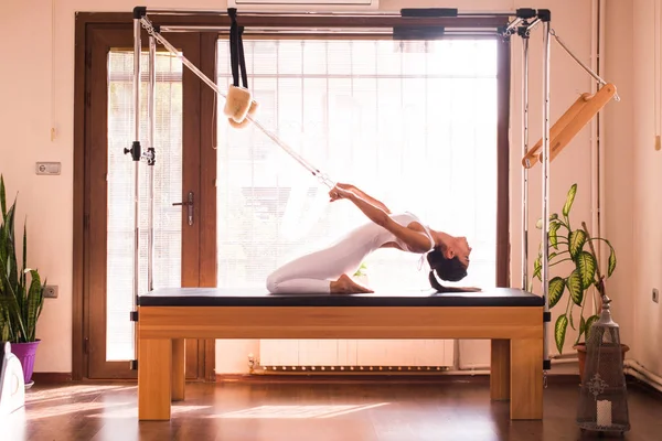 Genç kadın Pilates eğitmeni Pilates Reformer üzerinde egzersiz