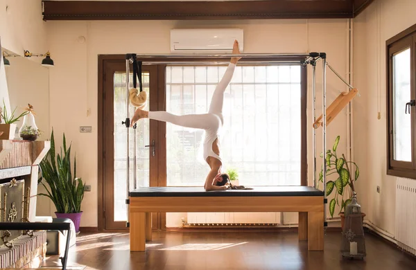 Genç kadın Pilates eğitmeni Pilates Reformer üzerinde egzersiz
