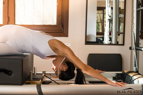 Genç kadın Pilates eğitmeni Pilates Reformer üzerinde egzersiz