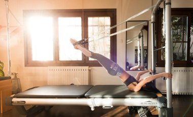 Genç kadın Pilates eğitmeni Pilates Reformer üzerinde egzersiz