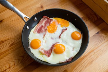 Güneşli tarafı yukarı yumurta pastırmalı bir tavada