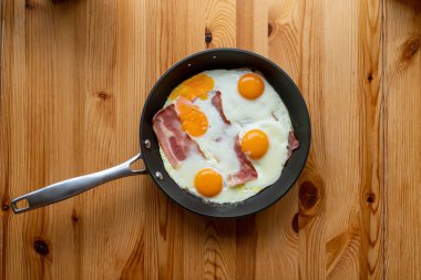 Güneşli tarafı yukarı yumurta pastırmalı bir tavada