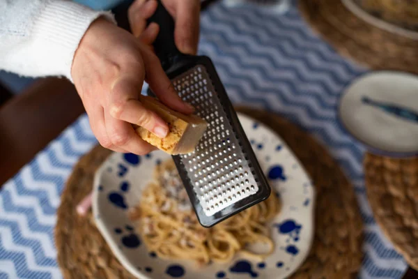 Vrouw handen raspen Parmezaanse kaas over pasta carbonara — Stockfoto