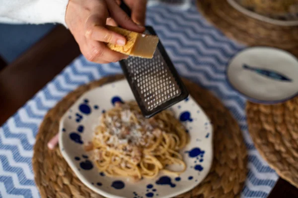 Mulher mãos ralando queijo parmesão em macarrão carbonara — Fotografia de Stock