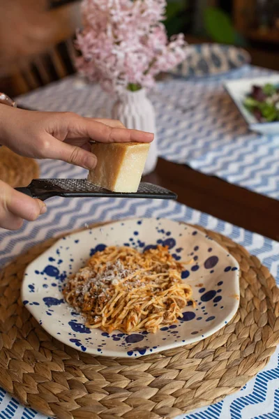 Manos de mujer rallando queso parmesano a bolonia de espaguetis caseros —  Fotos de Stock