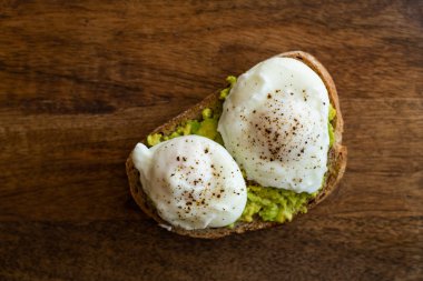 Haşlanmış yumurta ile avokado tost. Koyu ahşap yüzeyde hizmet