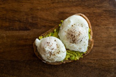 Haşlanmış yumurta ile avokado tost. Koyu ahşap yüzeyde hizmet