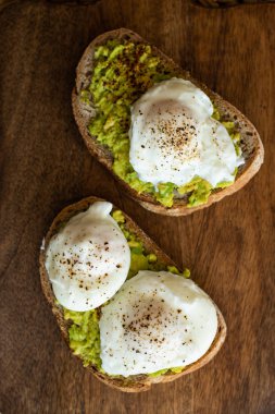 Haşlanmış yumurta ile avokado tost. Koyu ahşap yüzeyde hizmet