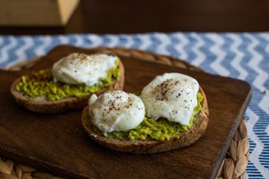 Haşlanmış yumurta ile avokado tost. Koyu ahşap yüzeyde hizmet