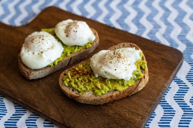 Haşlanmış yumurta ile avokado tost. Koyu ahşap yüzeyde hizmet