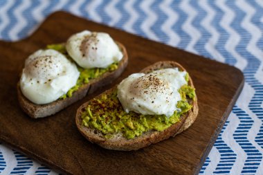 Haşlanmış yumurta ile avokado tost. Koyu ahşap yüzeyde hizmet
